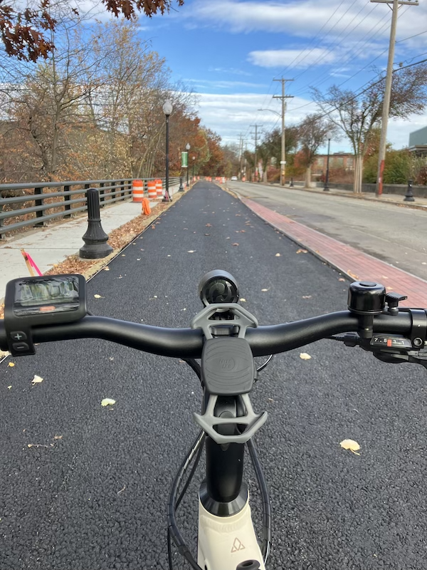 The handlebars of a ebike in the foreground, and a freshly-paved bike path stretching before me.